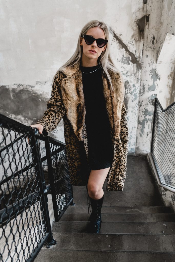 woman wearing animal print coat, boots and sunglasses