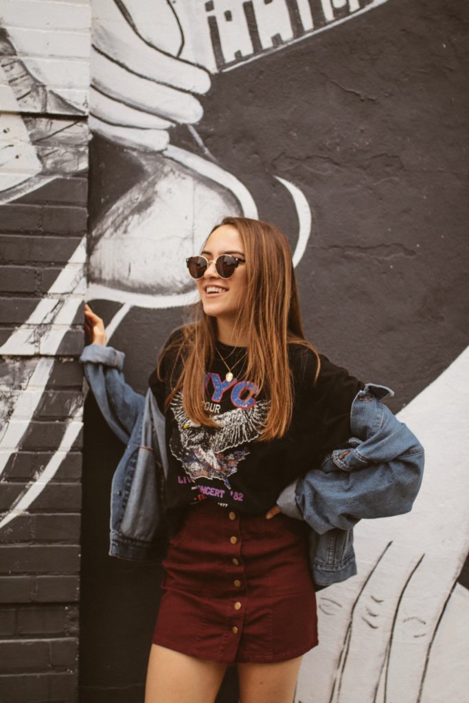 girl wearing a hip outfit and leaning on a wall